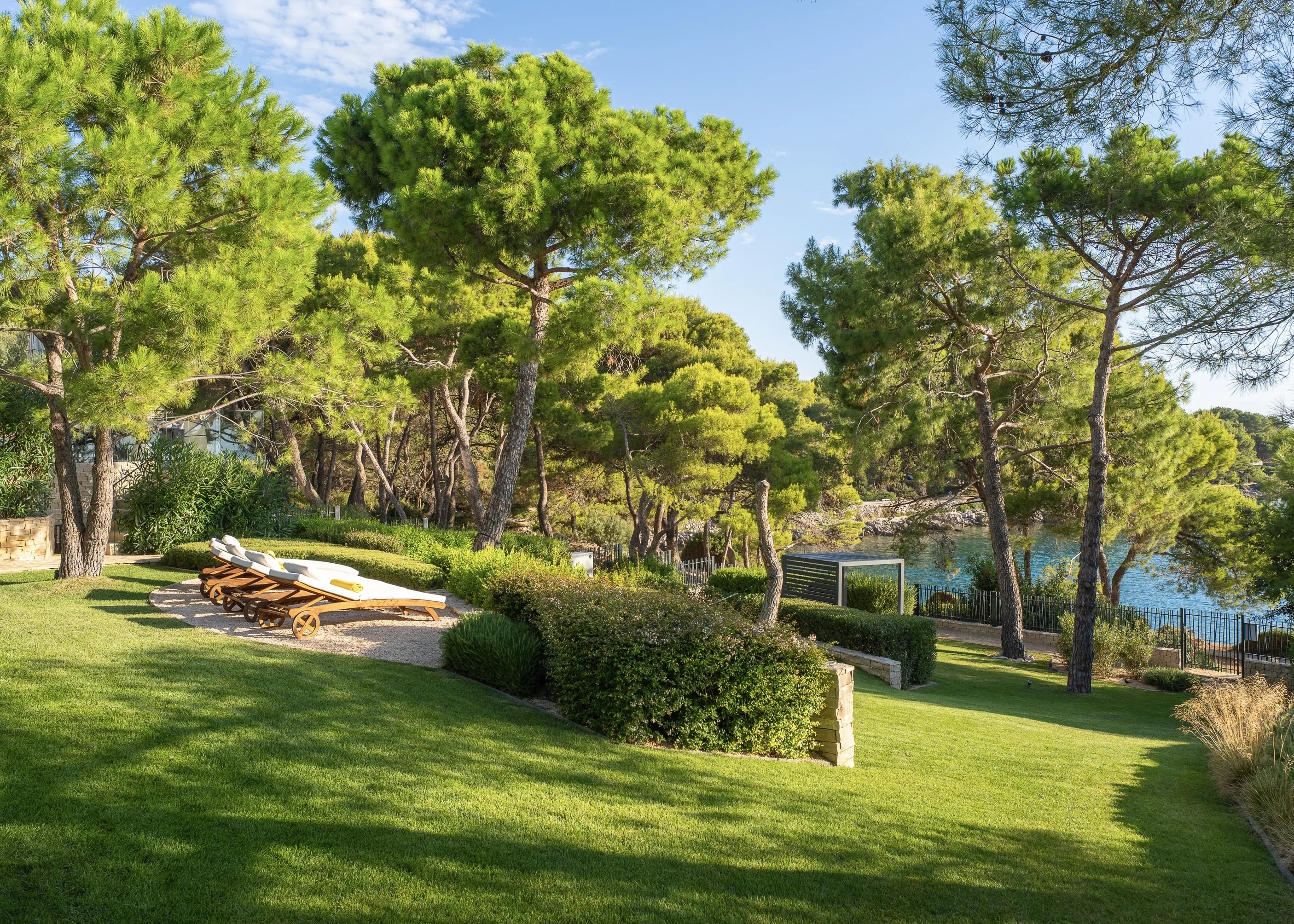 The lawn and its loungers screened by pines, the cove a few metres beyond