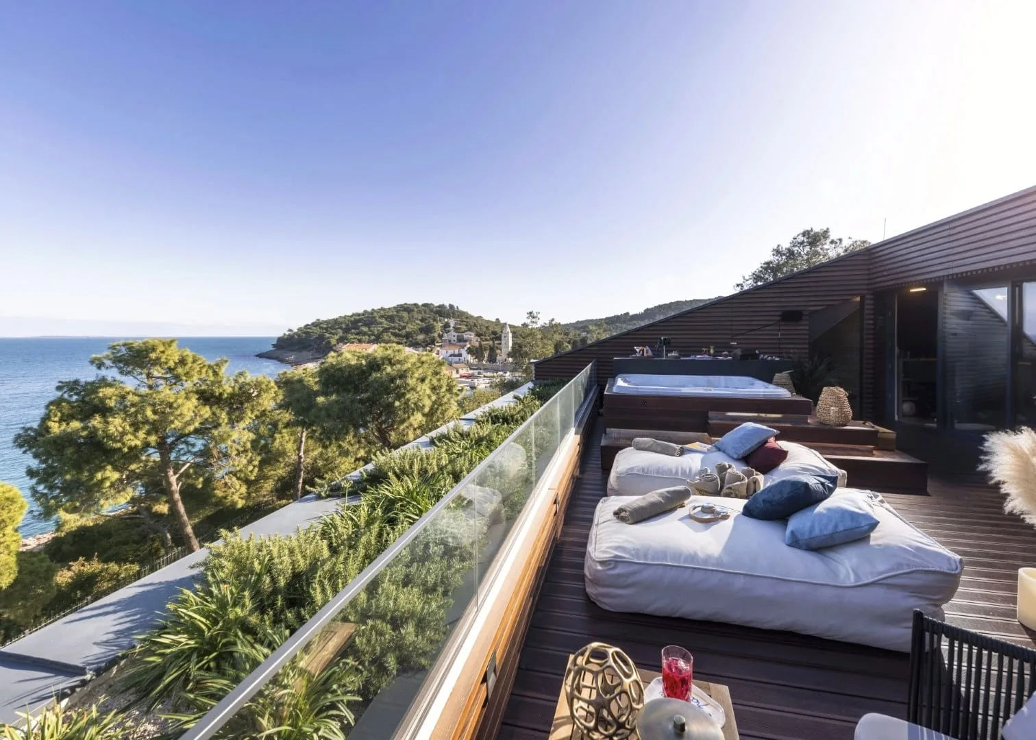 The rooftop terrace — daybeds and the jacuzzi above the cove